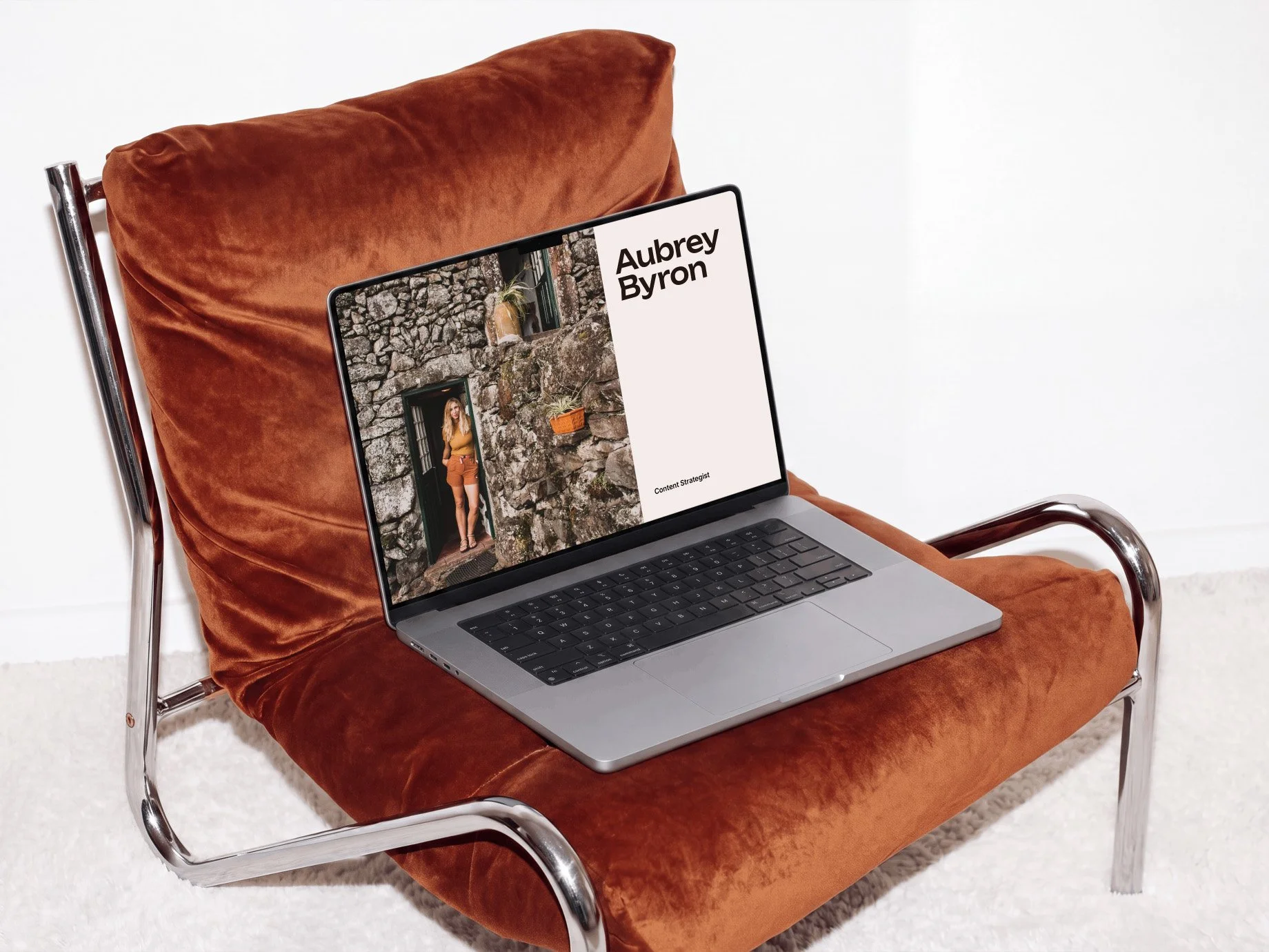 MacBook on a Metal Frame Chair is opened and showing a picture of Aubrey