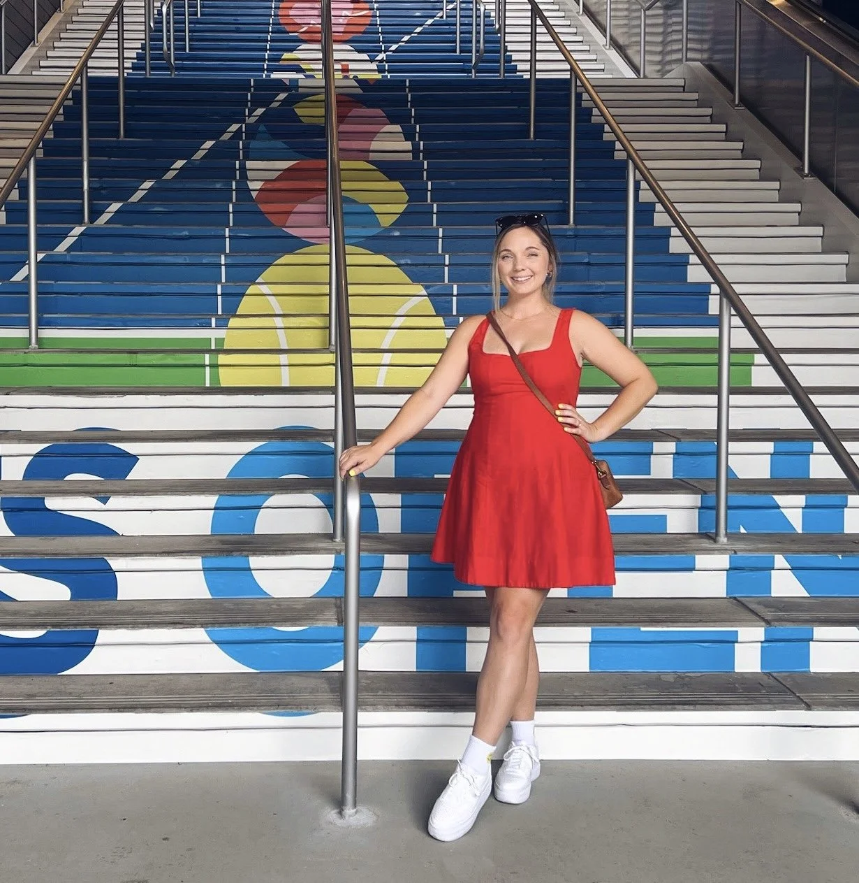 Chelsey Farris poses in front of her theme art installed on a staircase at the US Open