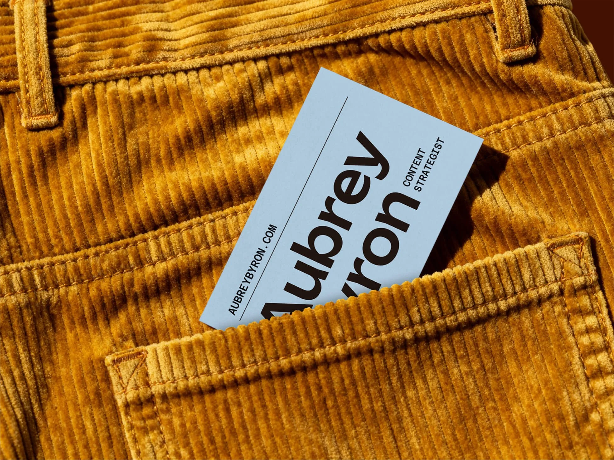 A business card peeks out the pocket of gold courduroy pants