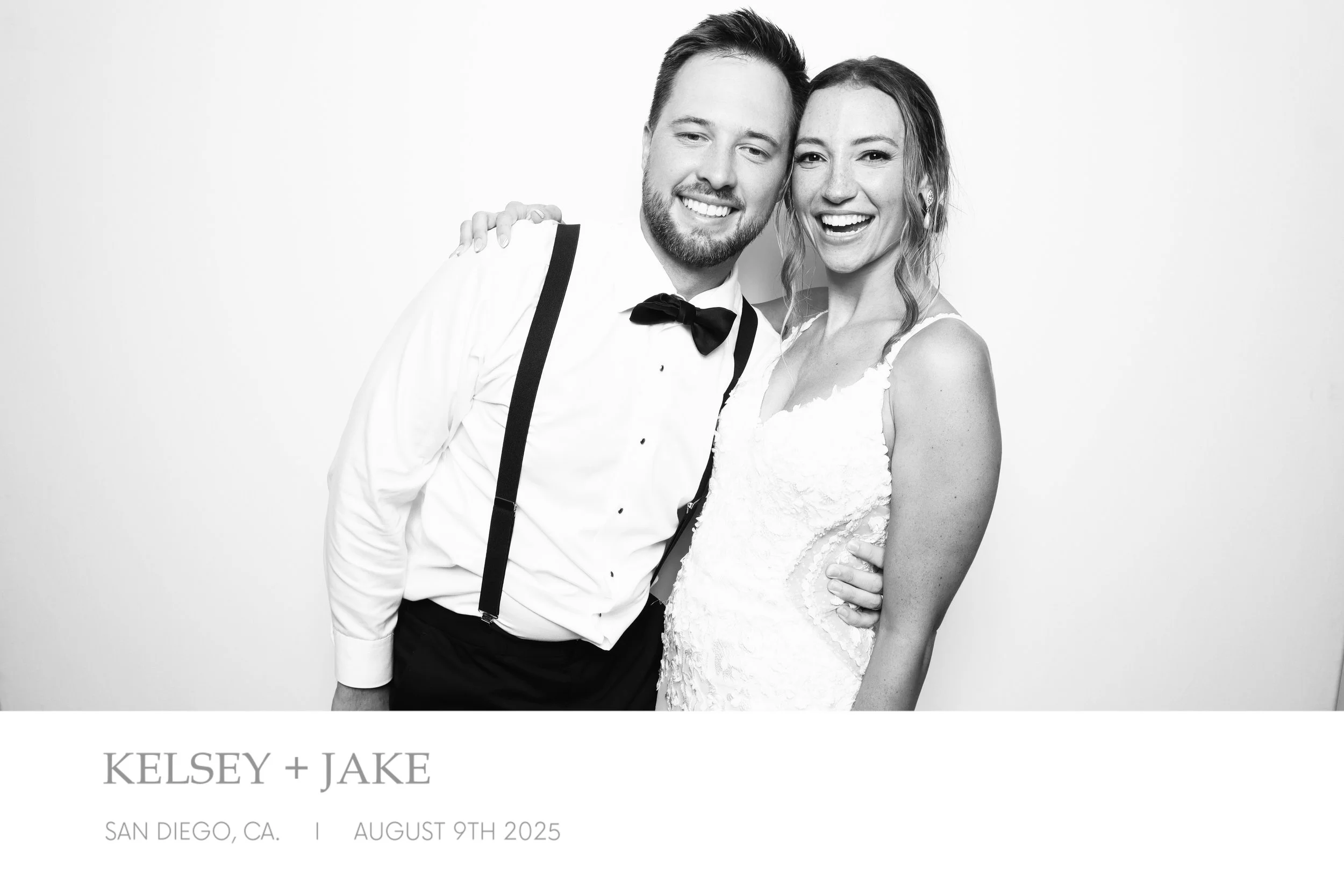 Black and white wedding photo of a happy couple, the groom in a tuxedo with suspenders and the bride in a wedding dress, smiling and embracing each other. Text overlay includes "Kelsey + Jake," "San Diego, CA," and "August 9th, 2025."