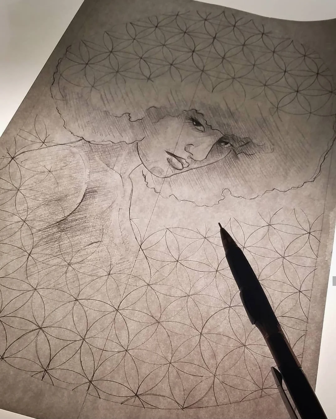 Sketch of a woman with curly hair, surrounded by a geometric pattern flower of life