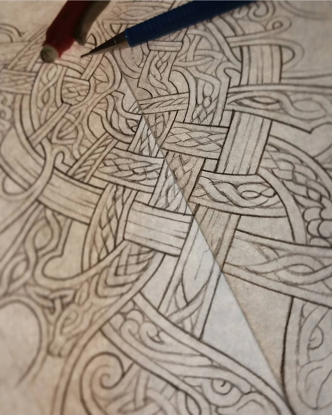 Close-up view of an intricate Celtic knot design being sketched with pencils on paper.