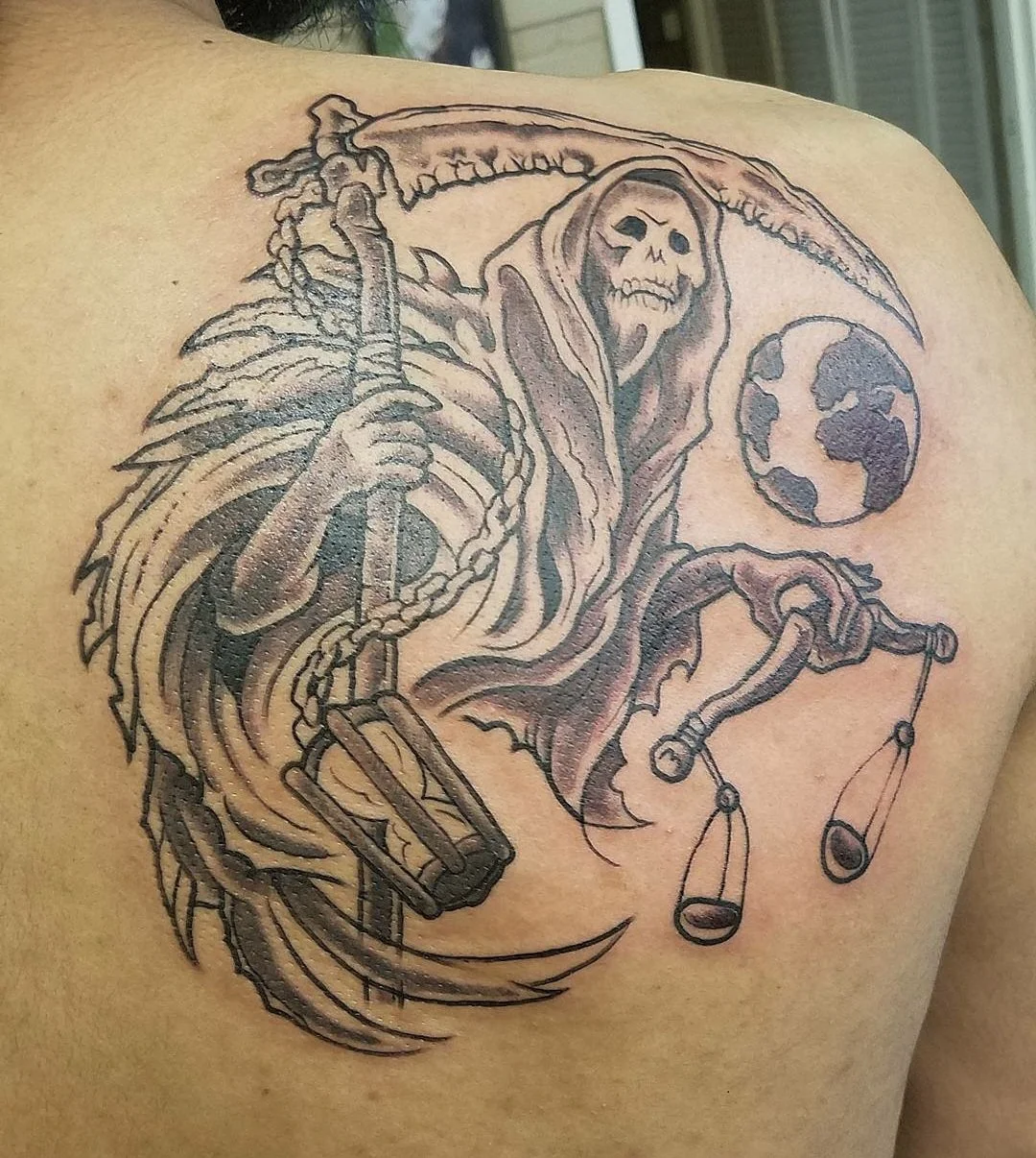 Tattoo of a grim reaper, holding a scythe and bone scales, with a planet earth in the background
