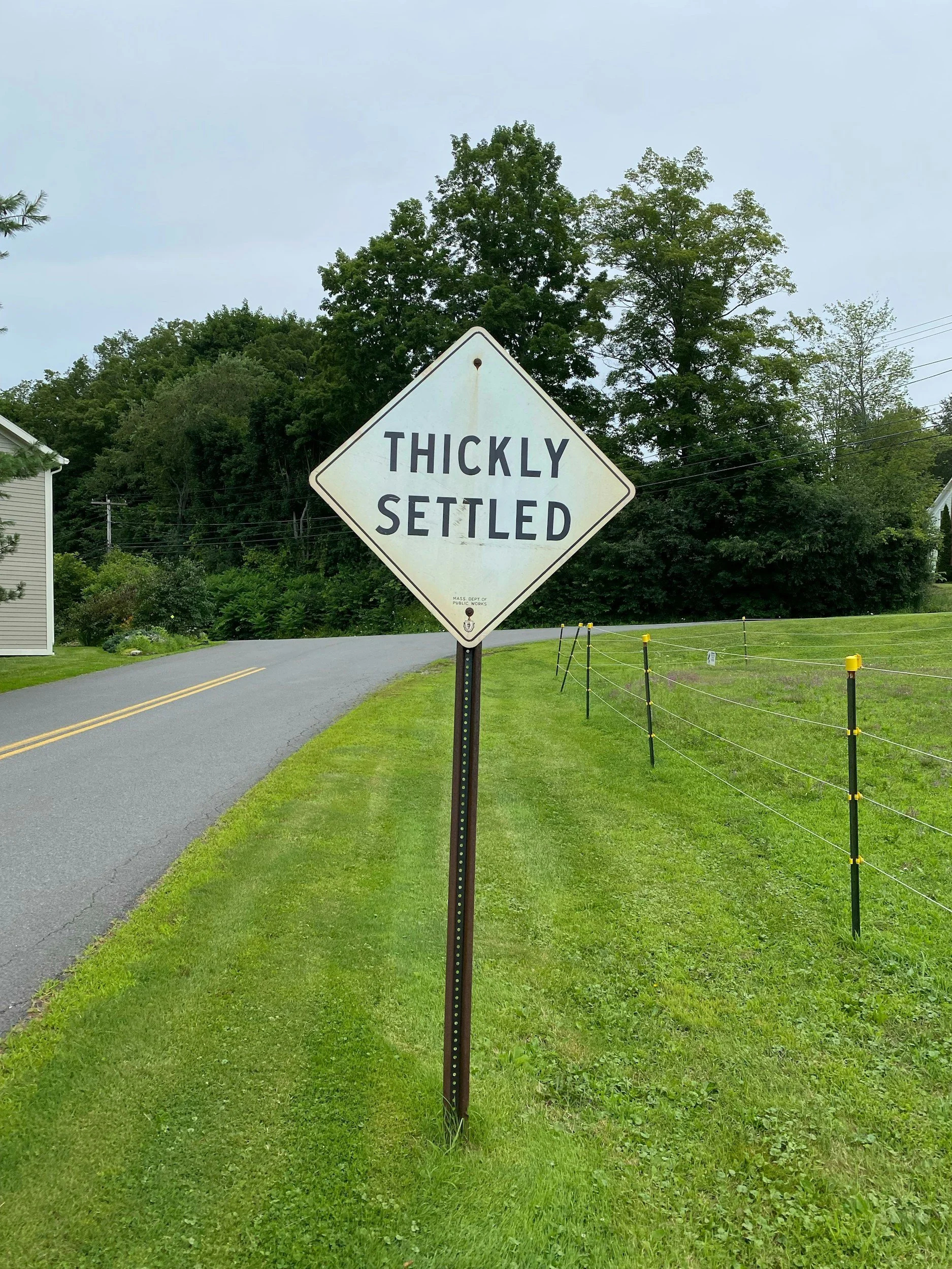 A yellow road sign that says thickly settled.