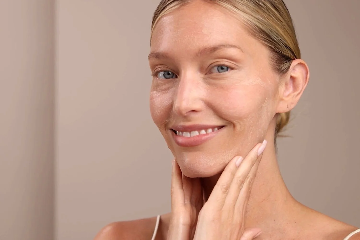 A woman applying the Eminence Organics Mango Exfoliating Enzyme Masque on their face