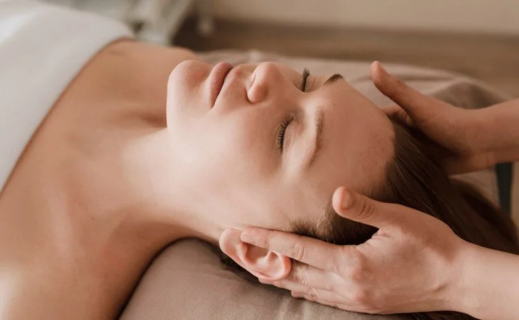 massage therapist placing their hands on either side of a client's head during craniosacral therapy