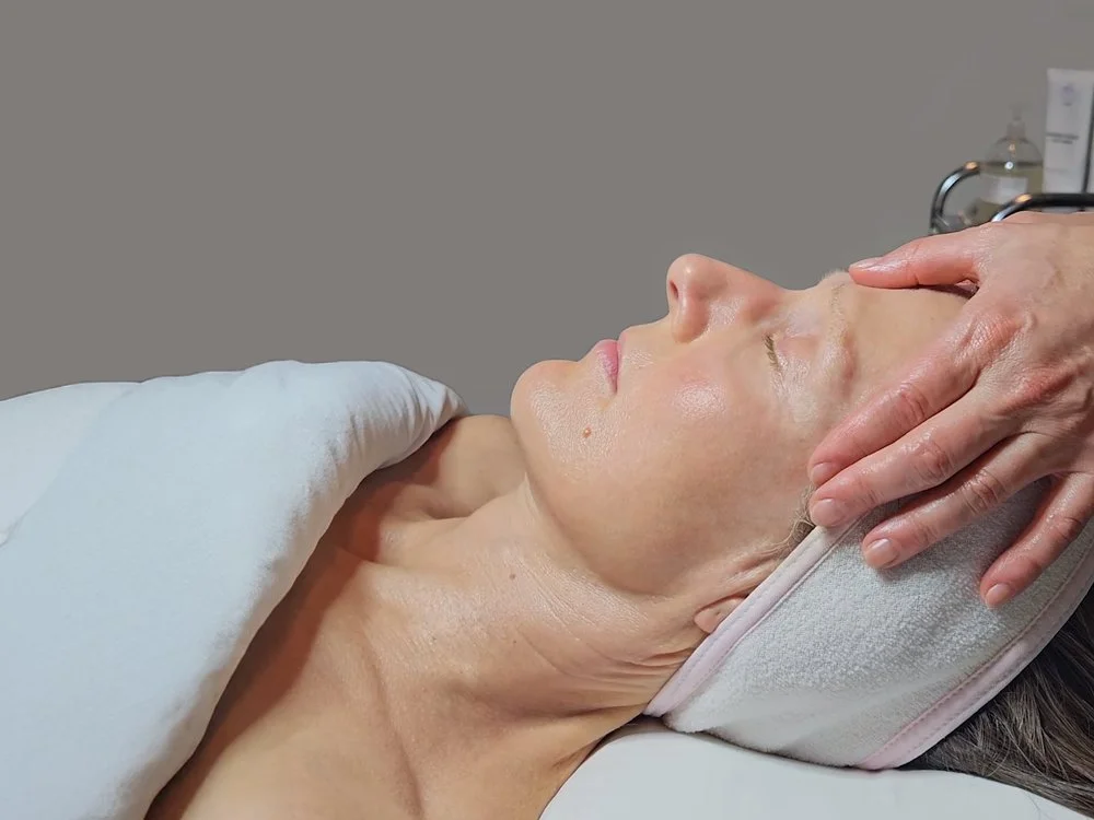 Esthetician applying gentle pressure on a woman's forehead during a facial massage