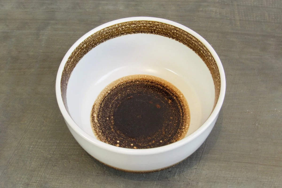 Top view of a white and brown glazed matcha bowl on a wood table