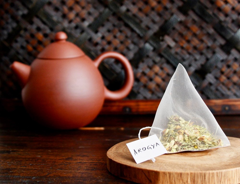 Arogya turmeric ginger tea in pyramid tea bag in front of yixing teapot