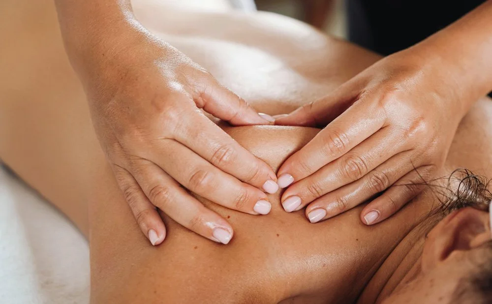 massage therapist gripping woman's back muscles during myofascial release therapy