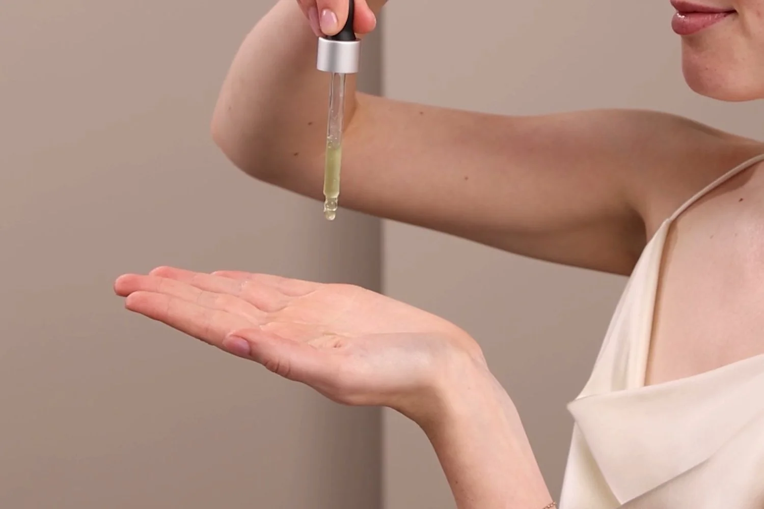 A woman applying the Eminence Organics Marine Flower Peptide Serum onto the palm of her hand