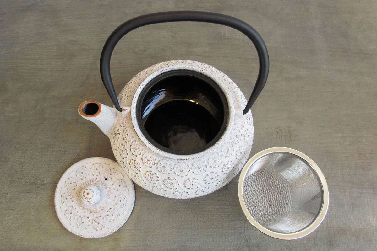 Top-down view of a white cast iron teapot showing its black enameled interior