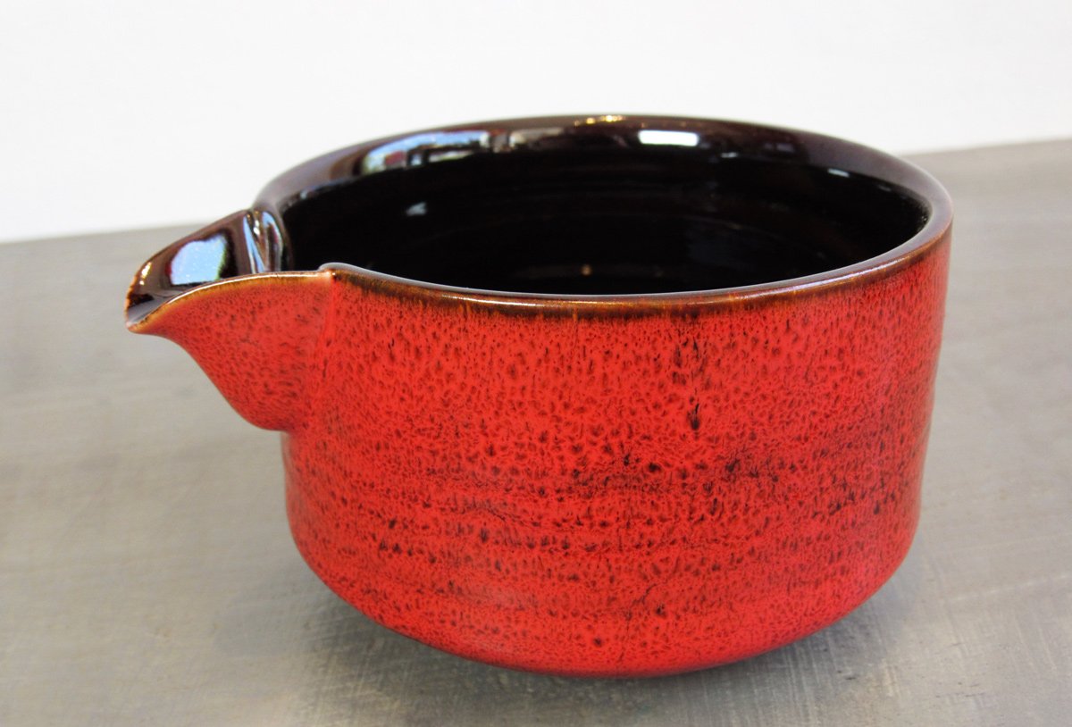 Closeup of red spouted matcha bowl with a dark-glazed interior