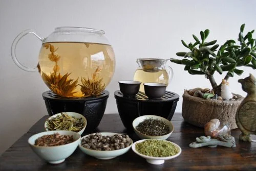 collection of loose leaf teas next to a teapot of brewed tea