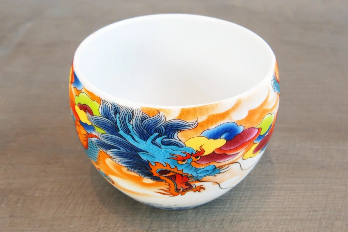 Top view of a teacup with a colorful dragon design with blue, orange, and red hues