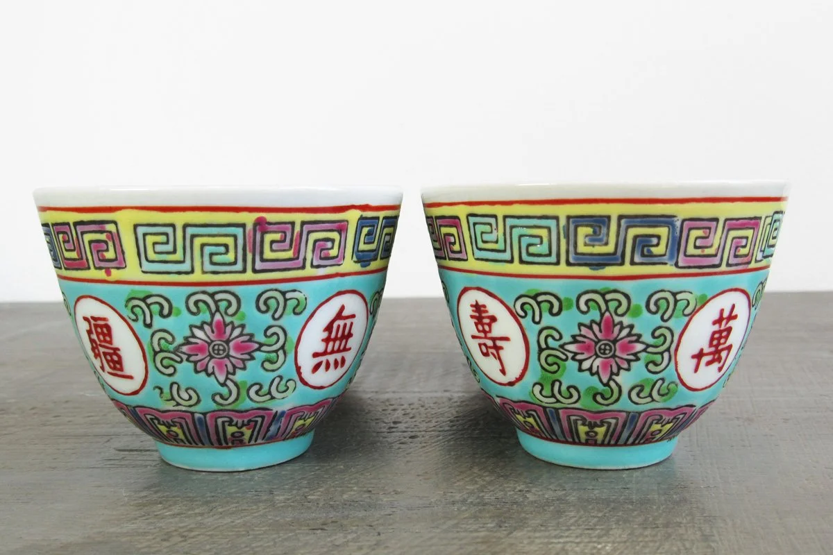 2 light turquoise teacups with hand-painted red Chinese characters and multicolor botanical patterns