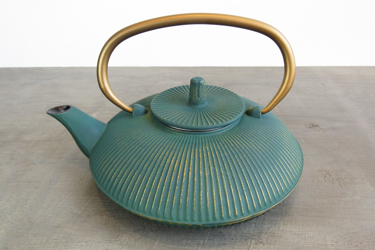 Teal cast iron teapot with a gold handle and golden accents