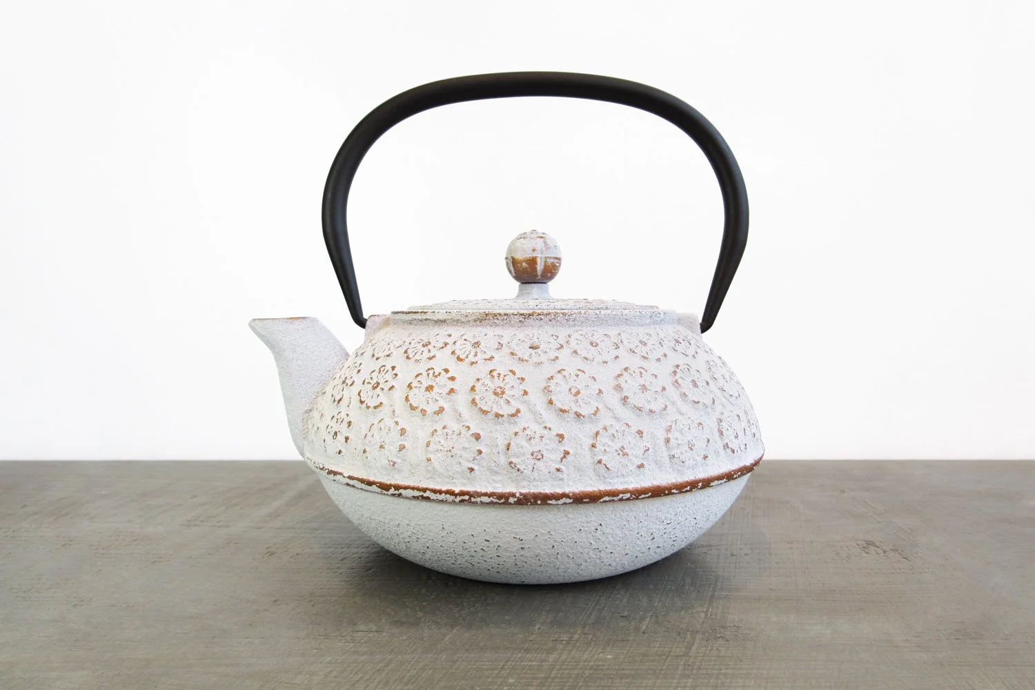 White cast iron teapot with a textured finish and raised floral details