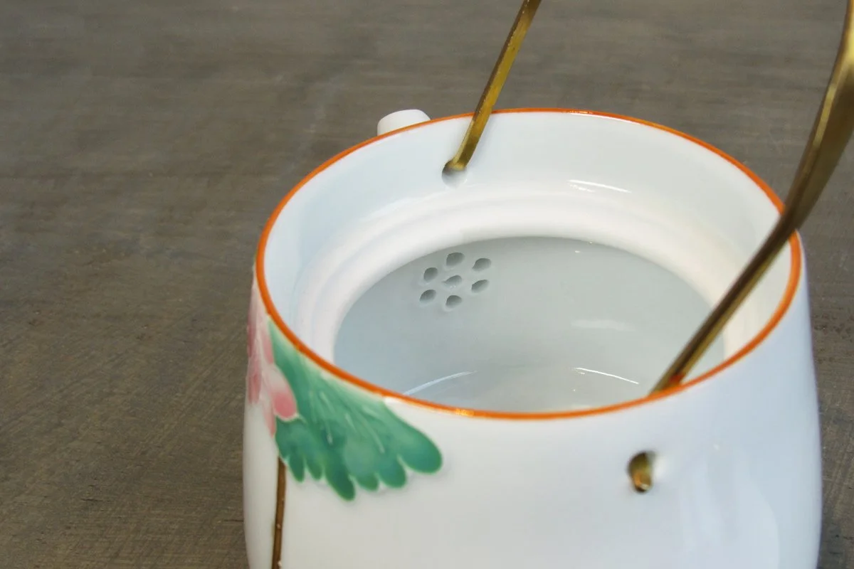Open teapot showing holes at the bottom of the spout