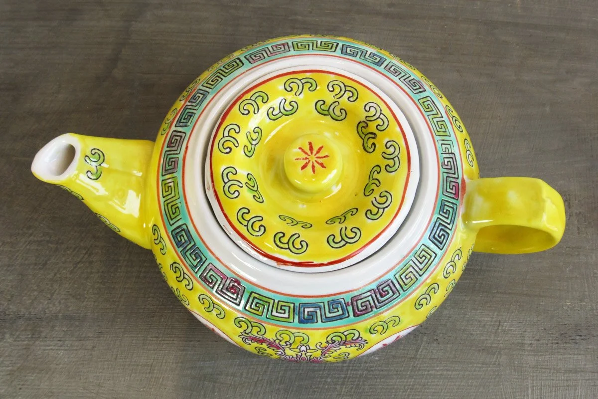 Top-down view of a yellow teapot with hand-painted botanical patterns