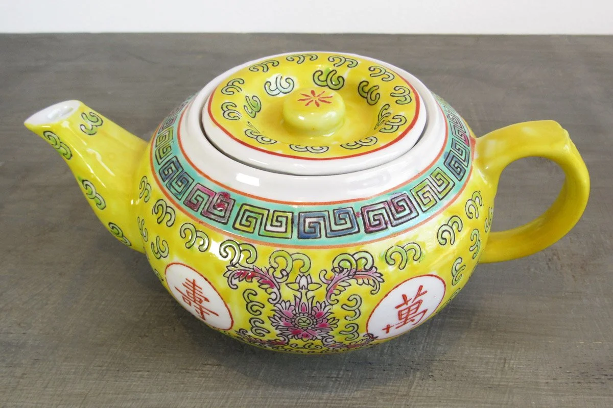 Yellow teapot with hand-painted red Chinese characters and multicolor botanical patterns