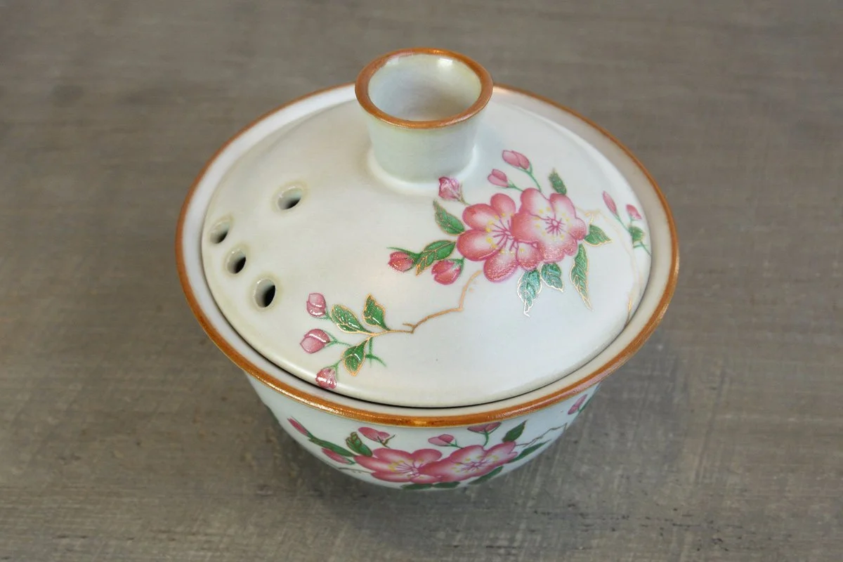 Top-down view of a crackle glaze gaiwan with a pink blossom design