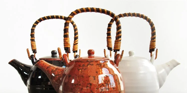 Three ceramic teapots with woven rattan handles