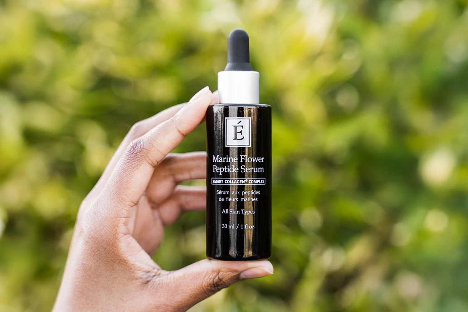 A hand holding the Eminence Organics Marine Flower Peptide Serum