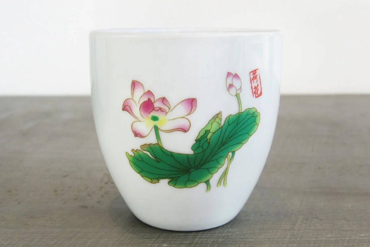 close up of white Chinese teacup with lotus flower pattern
