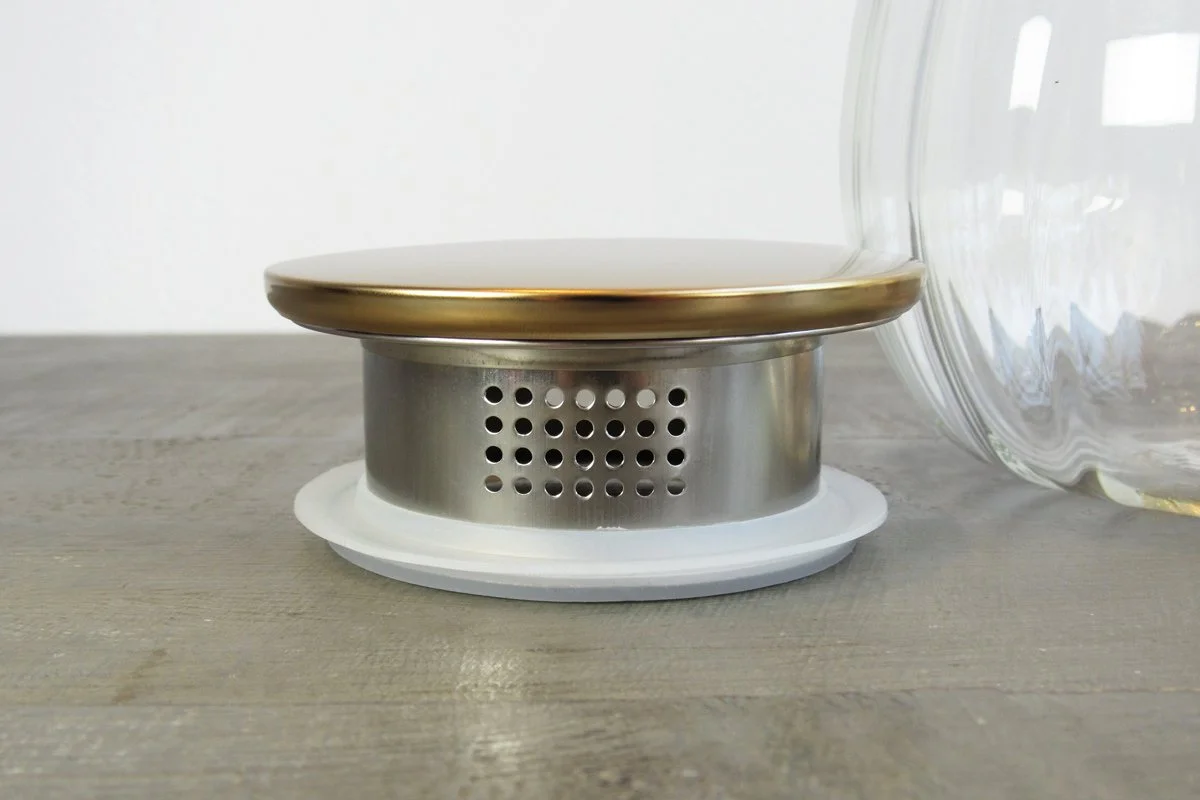 Close-up of the lid of a glass tea pitcher showing the built-in tea filter