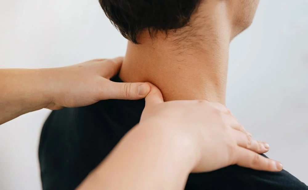 Massage therapist pressing their thumbs into a client’s neck during an acupressure session