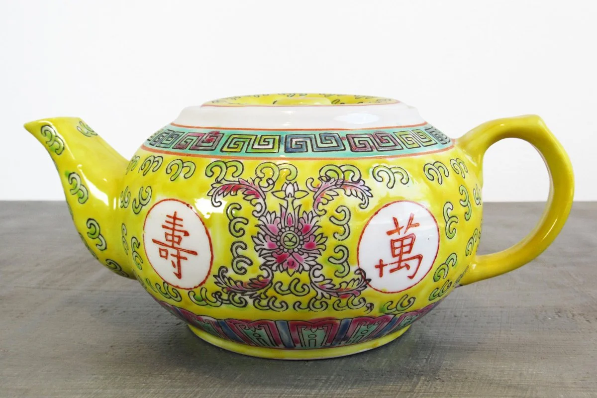 Yellow teapot with hand-painted red Chinese characters and multicolor botanical patterns