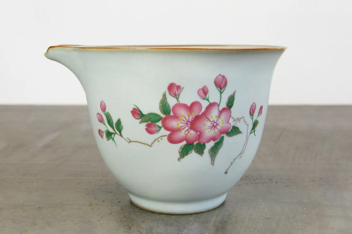 Close-up of a crackle glaze tea pitcher decorated with pink blossoms and buds