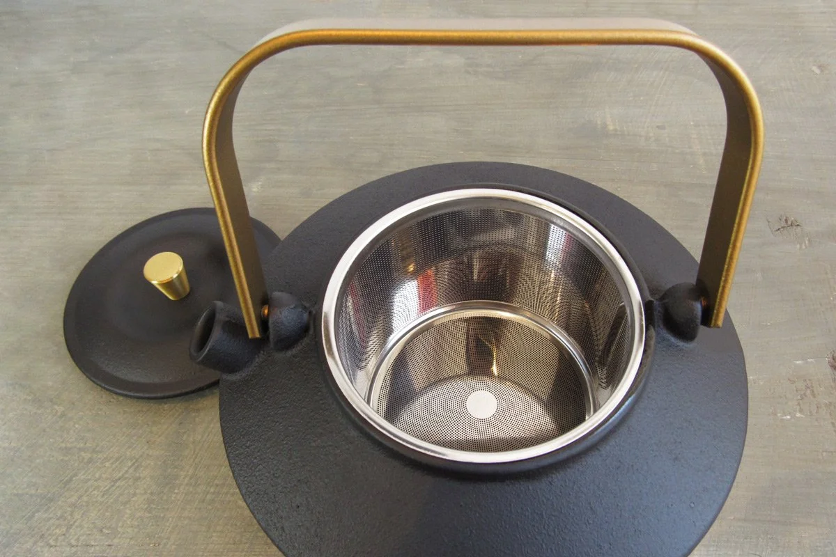 Open cast iron teapot showing the stainless steel infuser basket inside