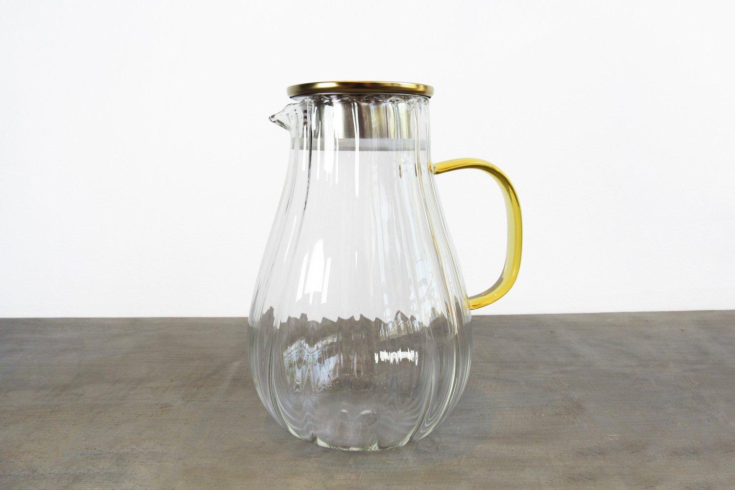 Fluted glass tea pitcher with a gold-colored lid and yellow glass handle