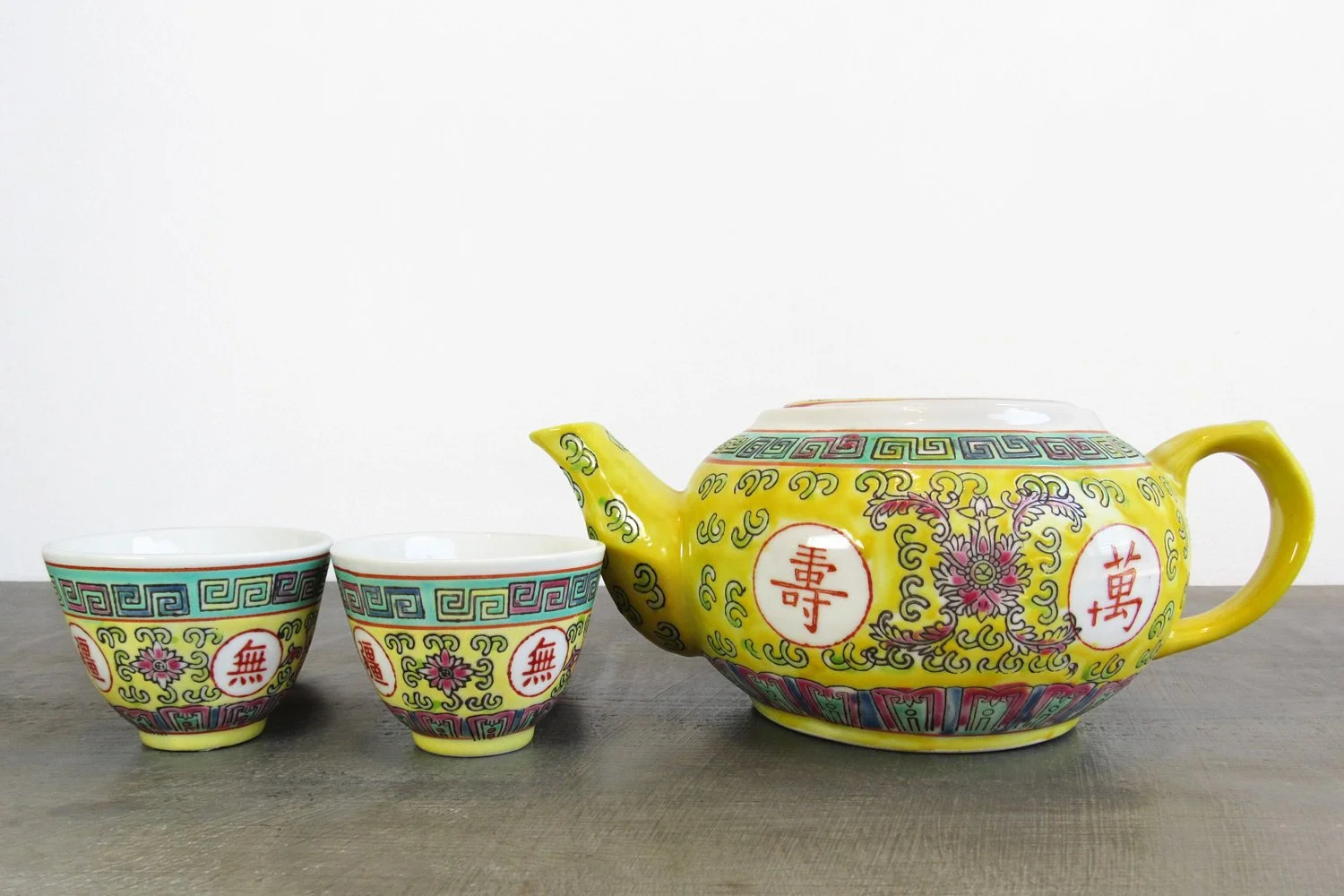 Yellow teapot and 2 teacups with hand-painted Chinese characters and botanical patterns