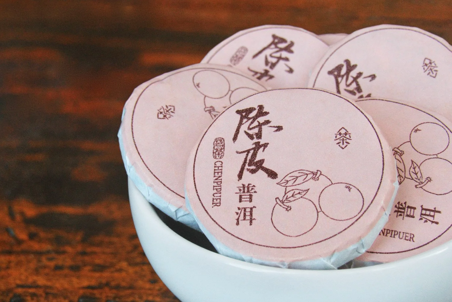 White bowl of wrapped mini tangerine pu'er tea cakes