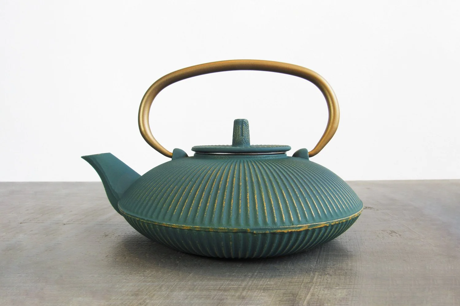 Teal cast iron teapot with a gold handle and a design of gold-brushed vertical stripes