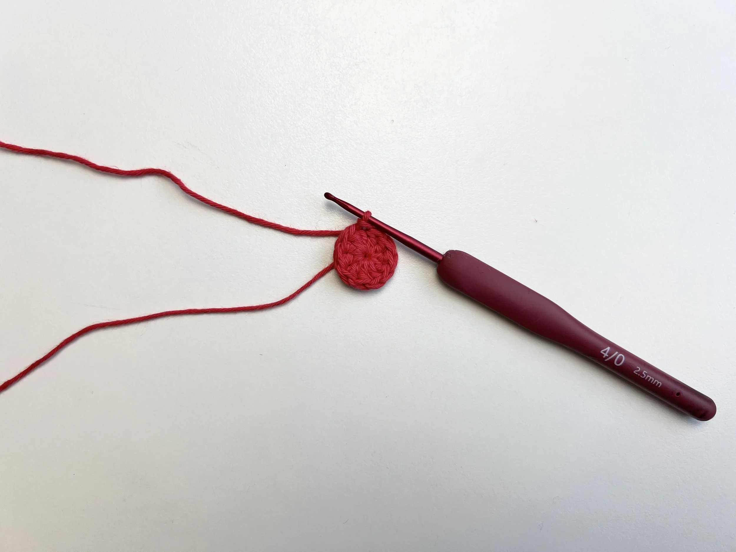  Small flat red circle being crocheted. 