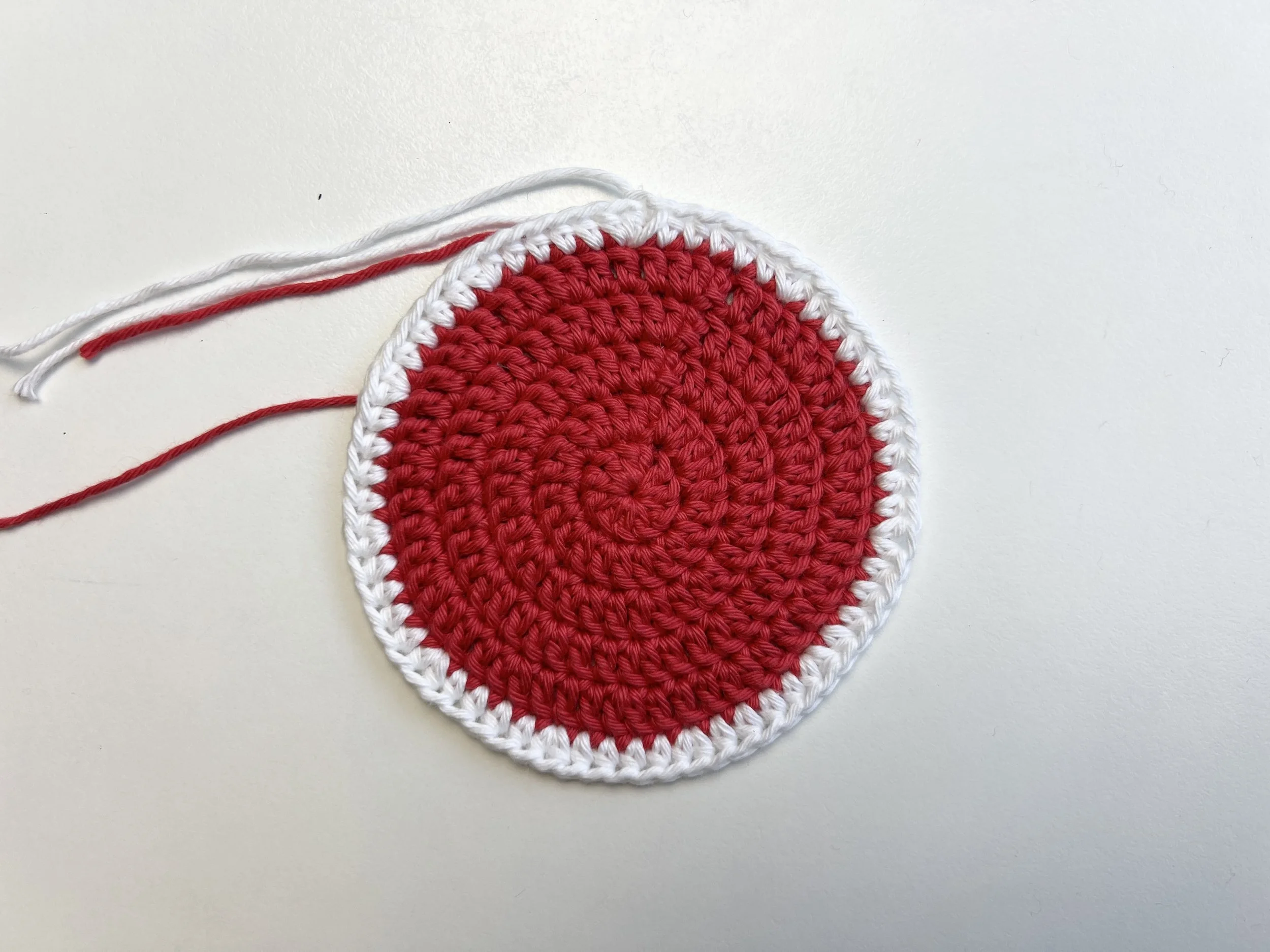  Crocheted flat red circle with a white border. 