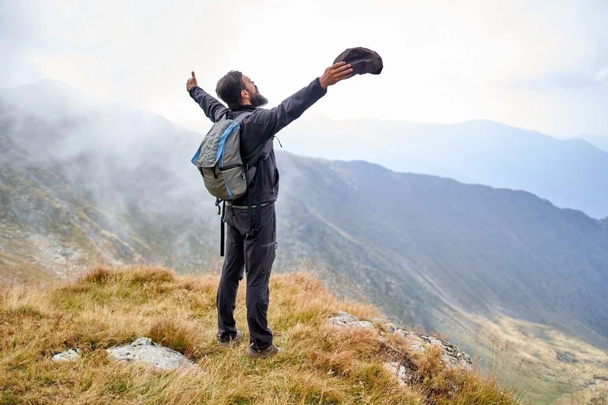 man on top of a mountain with his hands in the air. If you are an adult with ADHD and are struggling with executive functioning such as focus, impulse control, time management, organization, etc,. ACT Therapy in Middlesex, NJ can help.