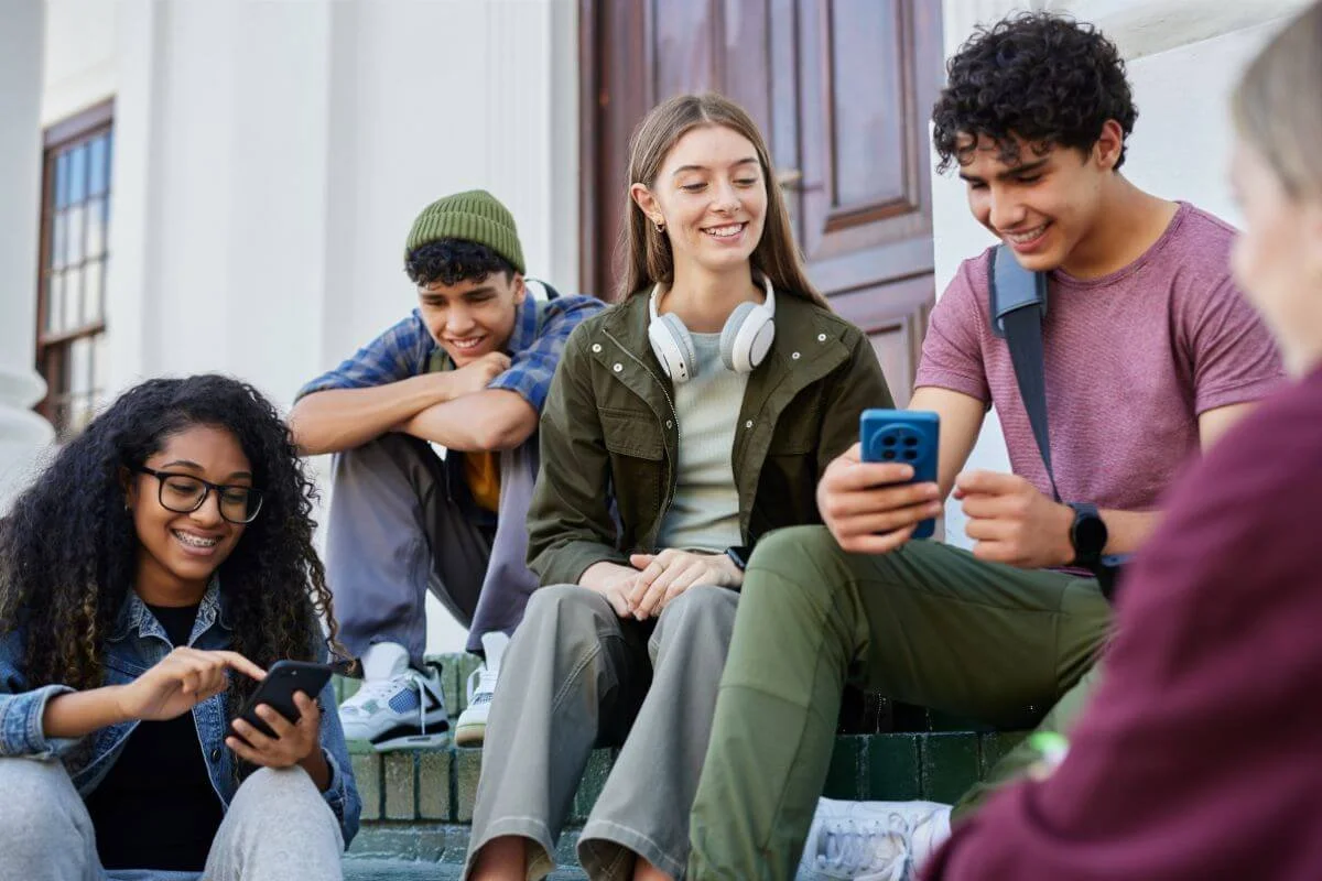 Five diverse teenagers sitting together outside representing teens ages 13 through 17 served by neurodiversity affirming ADHD and Autism evaluations at True Reflections MHS in Middlesex NJ