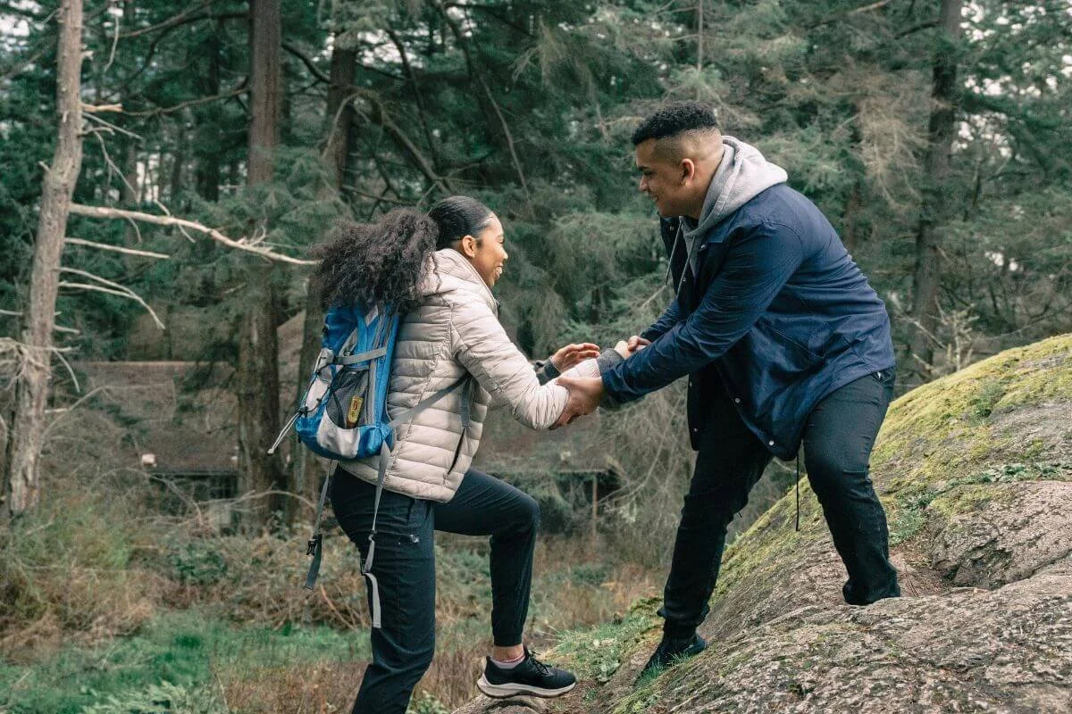 image of man helping a woman up a hill on a hike. If you need help in supporting your autistic partner schedule an appointment with a neurodivergent therapist in middlesex, nj today!