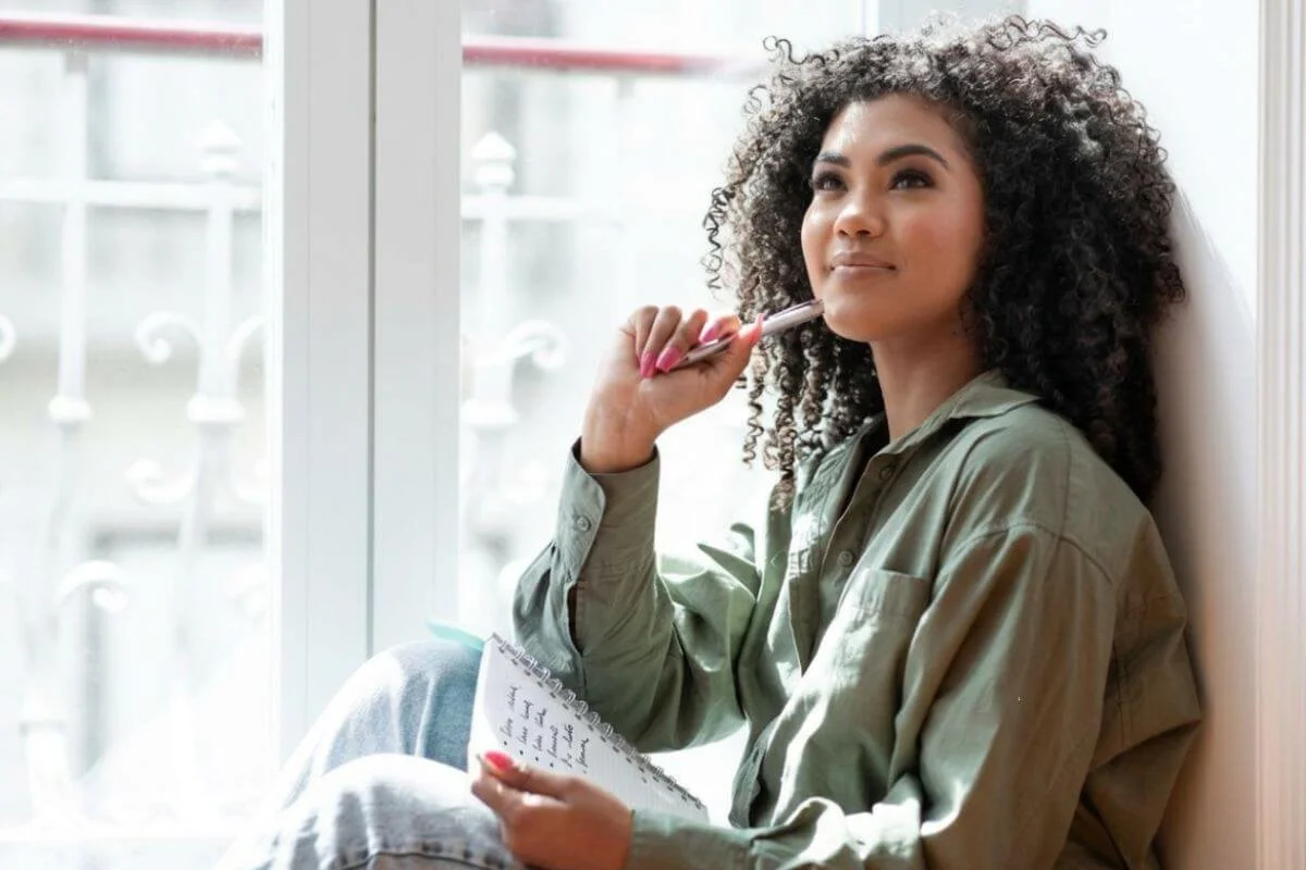 Adult woman sitting by window looking thoughtful and calm considering ADHD testing and Autism assessment in NJ