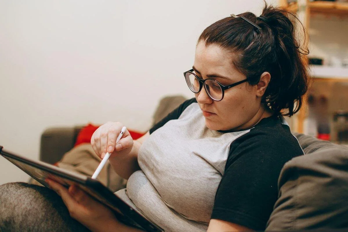 Image of girl sitting on couch using a table and stylus. If you have ADHD and are experiencing career struggles, schedule a neurovocational evaluation in New Jersey to find the right career with ADHD.