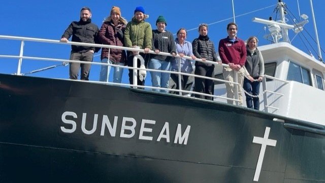 AHEC student group smile as they stand on the deck of the Sunbeam.