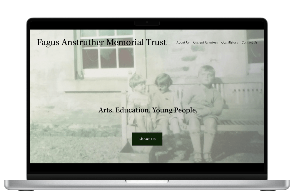 A laptop displaying the website of Fagus Anstruther Memorial Trust, featuring a vintage photo of three children sitting on a bench. Text reads "Arts. Education. Young People." with navigation options like About Us, Current Grantees, Our History, and Contact Us.
