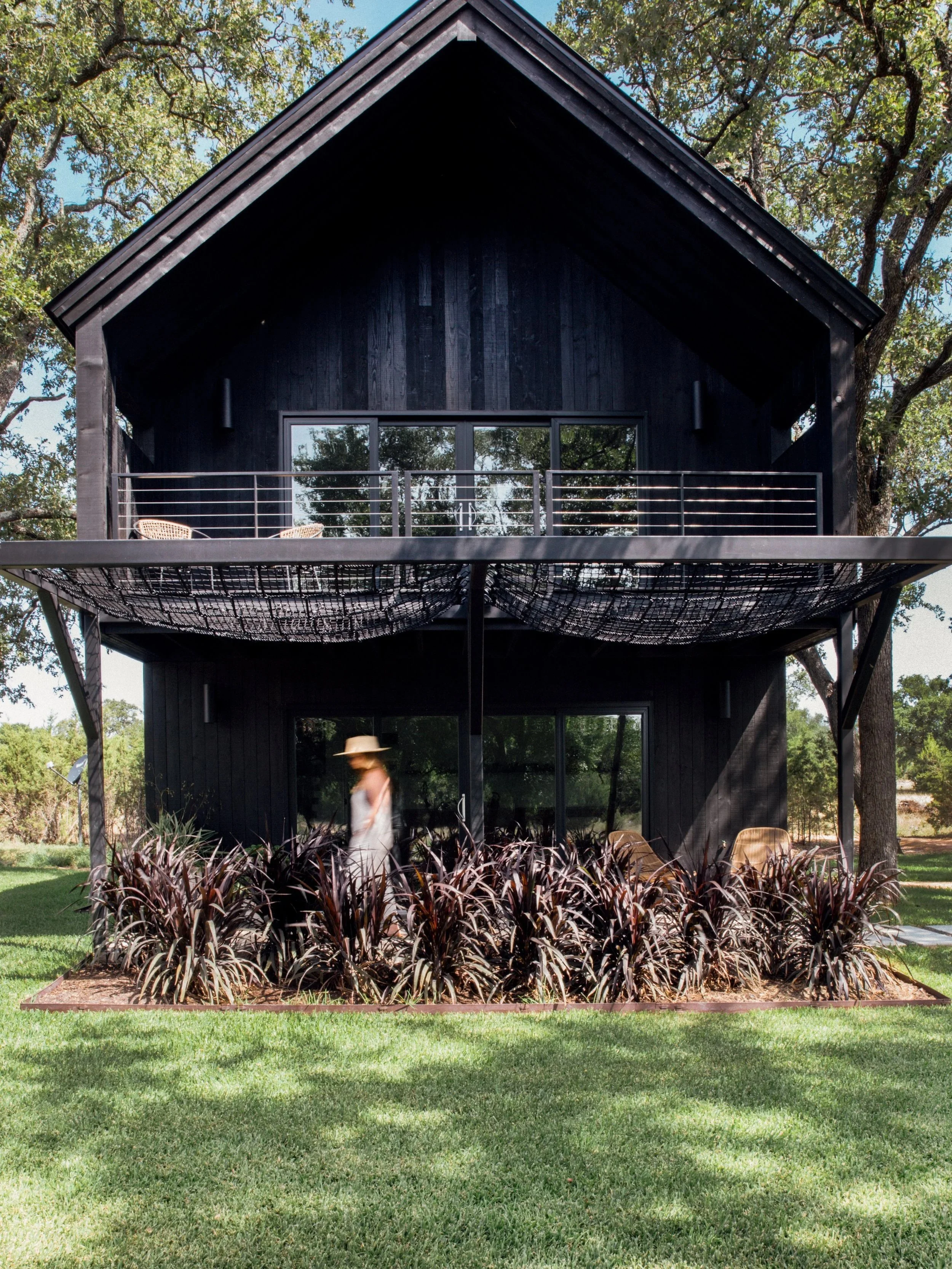 Modern black lodge with private hammock balcony surrounded by trees near Austin, Texas