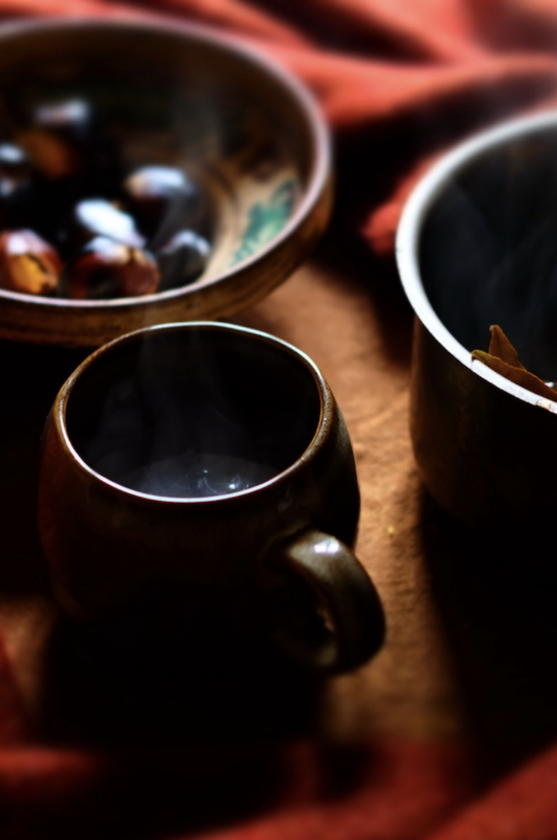 Three tea or coffee cups and bowls on a wooden surface with a red cloth underneath.