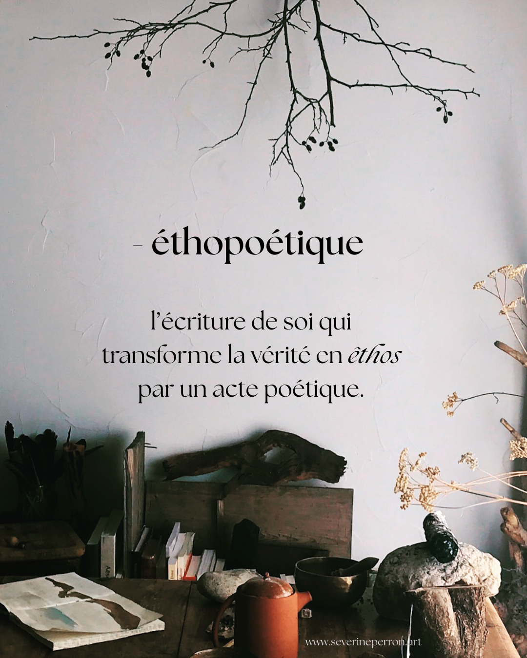A wall with a hanging branch illustration and French text about 'ethopoetics,' describing it as the writing of the self that transforms truth into ethics through poetic acts. A table with various objects, books, a ceramic mug, stones, and dried plants is also visible.